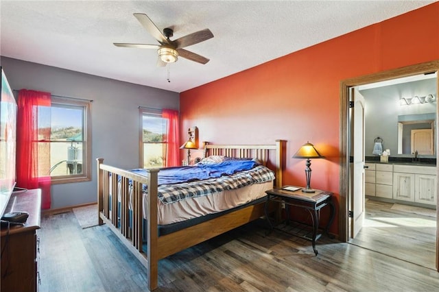 bedroom with hardwood / wood-style flooring, connected bathroom, sink, and a textured ceiling