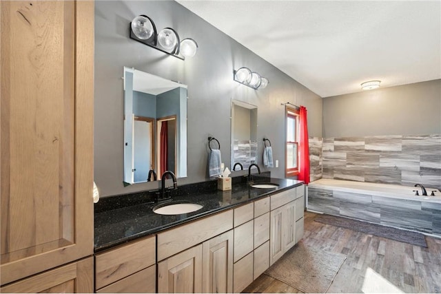 bathroom featuring vanity, tiled tub, and hardwood / wood-style floors