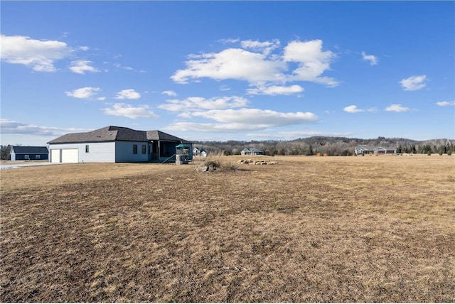 view of yard featuring a rural view and a garage