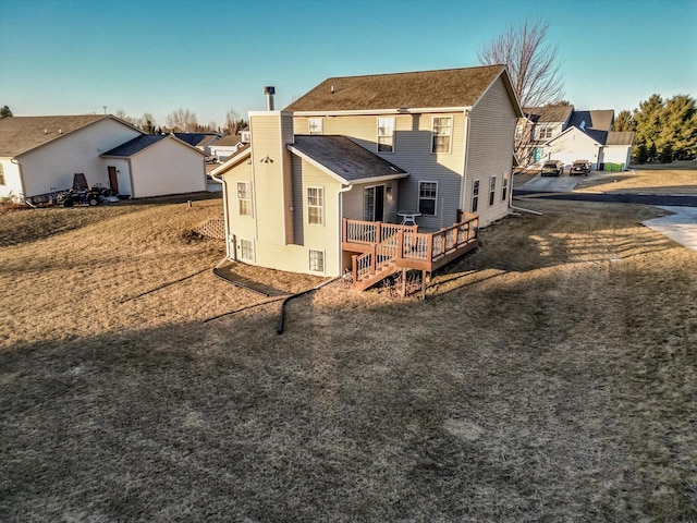 back of house with a wooden deck and a lawn