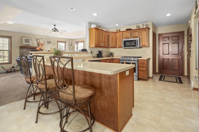 kitchen with appliances with stainless steel finishes, sink, a kitchen breakfast bar, ceiling fan, and kitchen peninsula