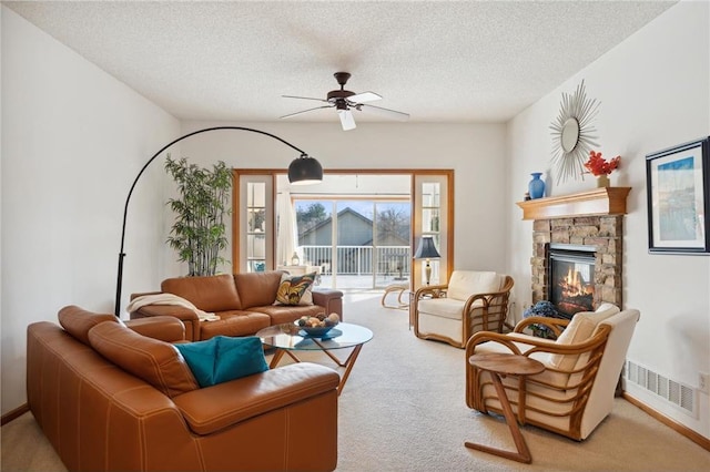 carpeted living room featuring ceiling fan, a fireplace, and a textured ceiling