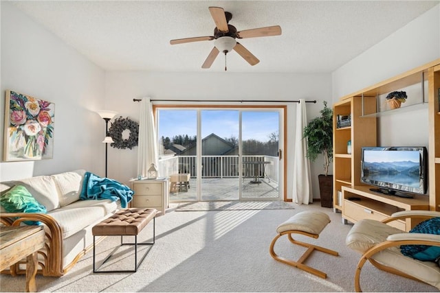 living room featuring ceiling fan, light carpet, and a textured ceiling