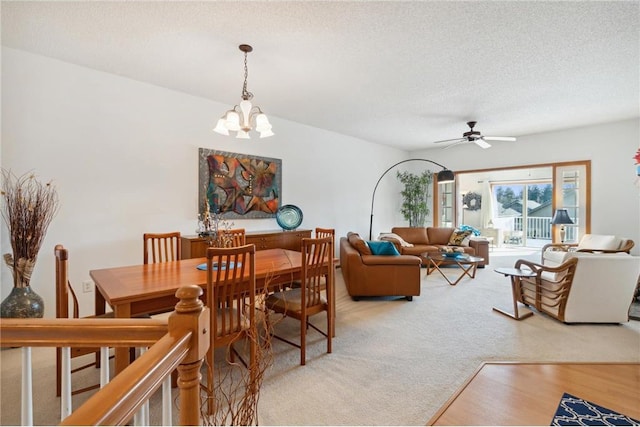 dining area with carpet flooring, ceiling fan with notable chandelier, and a textured ceiling