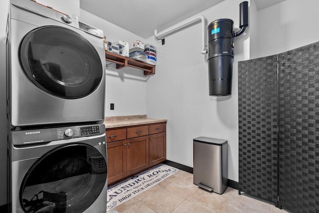 clothes washing area featuring stacked washing maching and dryer and light tile patterned floors