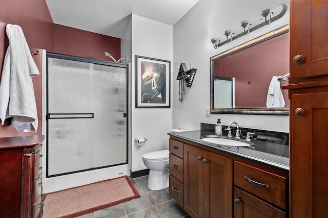 bathroom featuring a shower with door, vanity, tile patterned flooring, and toilet