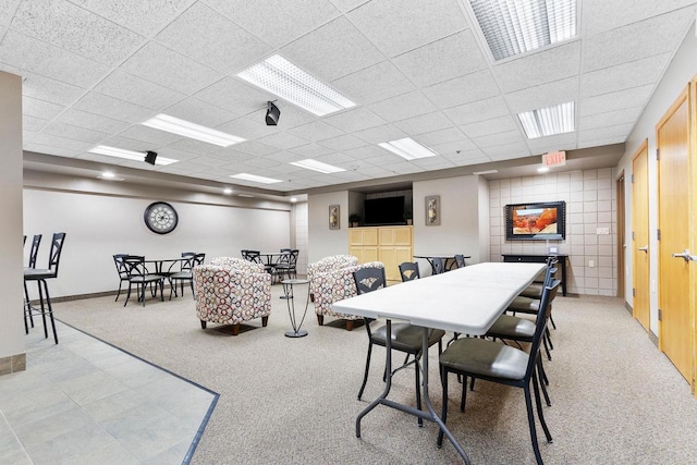 carpeted dining space featuring a paneled ceiling