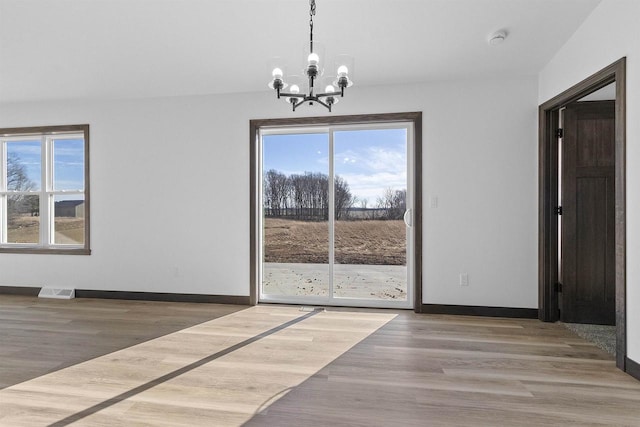 unfurnished dining area featuring hardwood / wood-style flooring and a notable chandelier