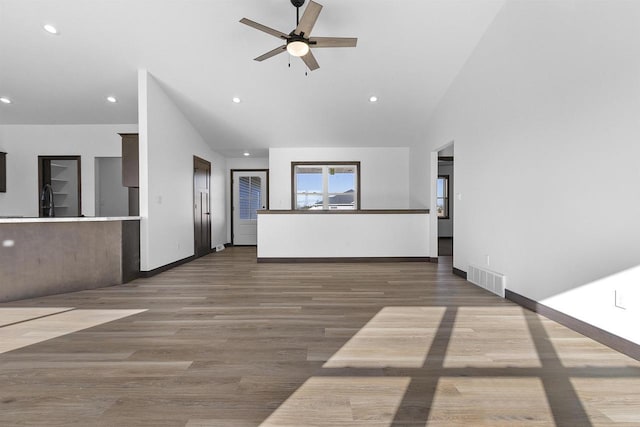 unfurnished living room with ceiling fan, high vaulted ceiling, sink, and hardwood / wood-style floors