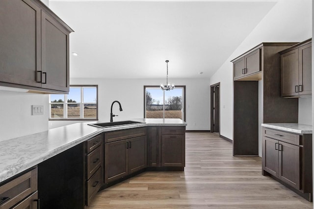 kitchen featuring sink, hanging light fixtures, dark brown cabinetry, a notable chandelier, and light wood-type flooring