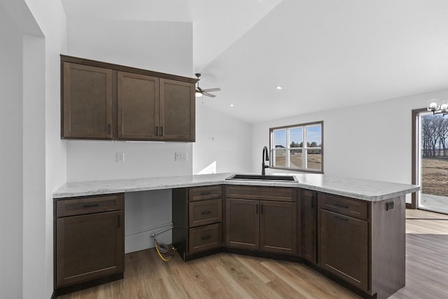 kitchen with lofted ceiling, sink, dark brown cabinets, kitchen peninsula, and light wood-type flooring