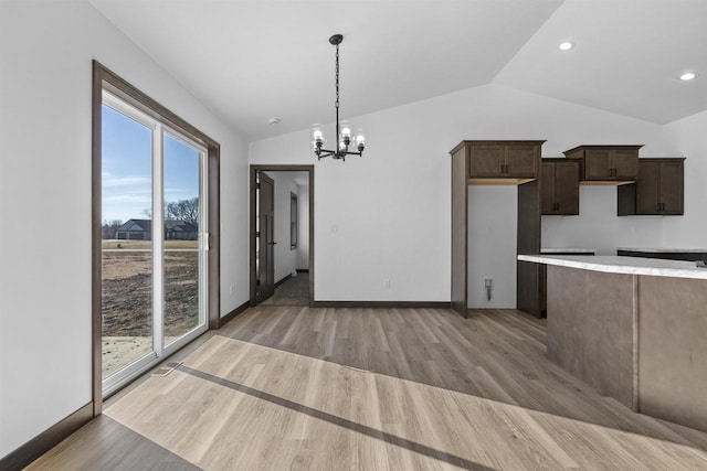 kitchen featuring dark brown cabinetry, an inviting chandelier, vaulted ceiling, light hardwood / wood-style flooring, and pendant lighting