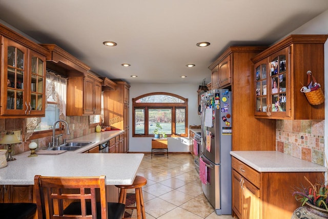 kitchen with appliances with stainless steel finishes, sink, backsplash, a kitchen bar, and light tile patterned floors