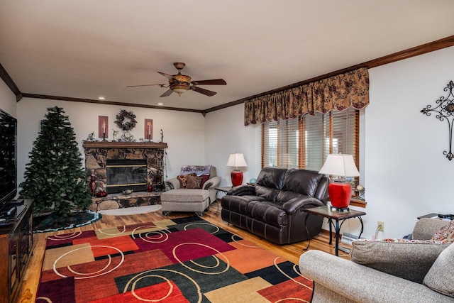 living room with hardwood / wood-style floors, crown molding, a fireplace, and ceiling fan