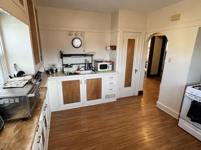 kitchen with white appliances, dark hardwood / wood-style flooring, sink, and white cabinets