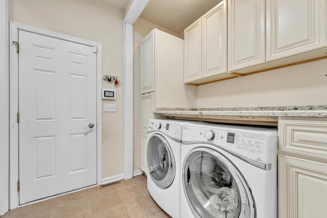 washroom with cabinets, washer and dryer, and light tile patterned floors