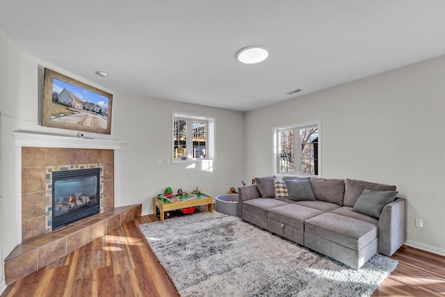 living room with a tile fireplace and wood-type flooring