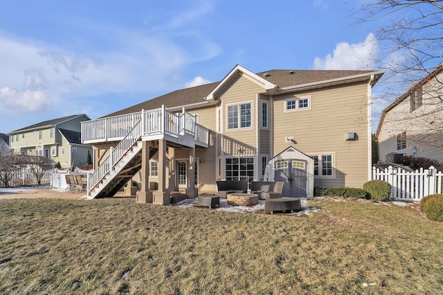 back of property featuring a wooden deck, a fire pit, a lawn, and a patio