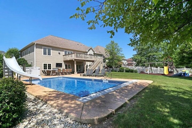 view of pool with a patio, a water slide, a deck, and a lawn