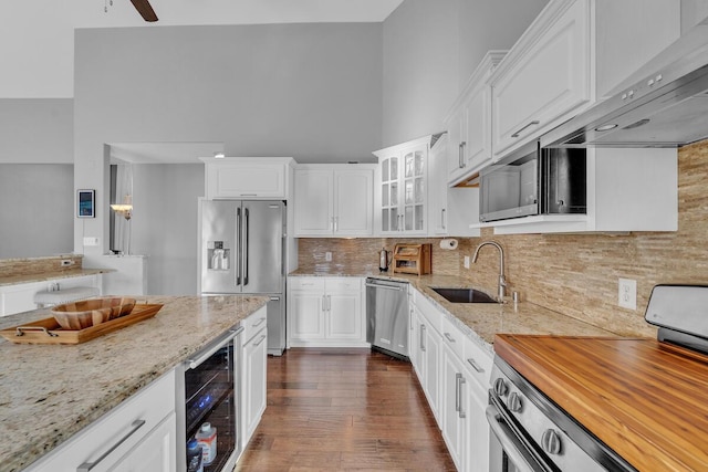 kitchen with sink, white cabinetry, stainless steel appliances, beverage cooler, and light stone countertops