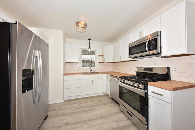 kitchen featuring white cabinetry, appliances with stainless steel finishes, wooden counters, and hanging light fixtures