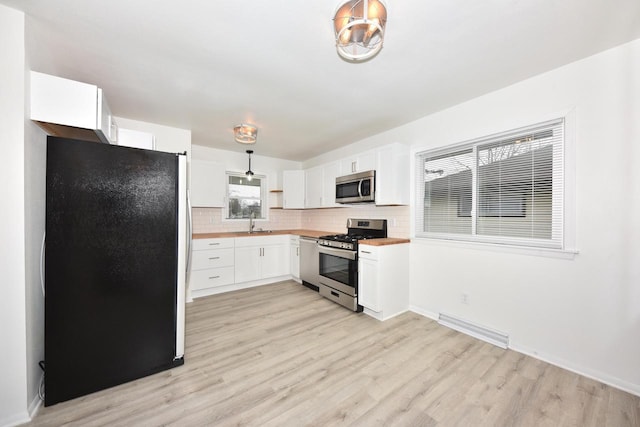 kitchen with pendant lighting, light hardwood / wood-style flooring, white cabinets, and appliances with stainless steel finishes