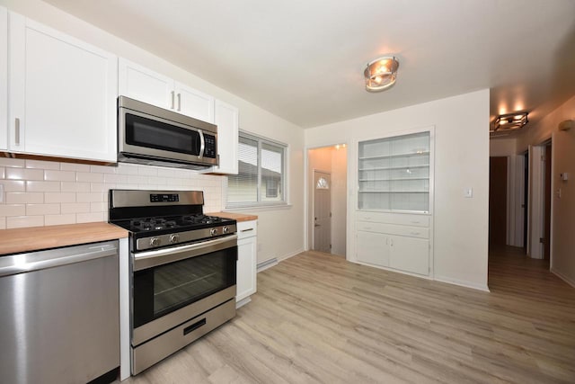 kitchen with butcher block counters, stainless steel appliances, light hardwood / wood-style floors, white cabinets, and decorative backsplash