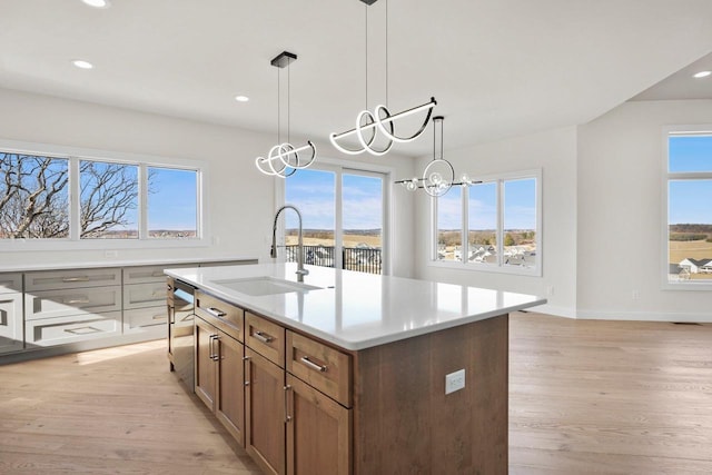 kitchen featuring dishwasher, pendant lighting, a kitchen island with sink, and sink