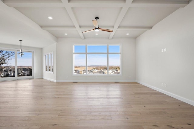 unfurnished living room with beamed ceiling, a healthy amount of sunlight, coffered ceiling, and light hardwood / wood-style floors