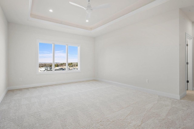 unfurnished room with crown molding, a tray ceiling, light colored carpet, and ceiling fan