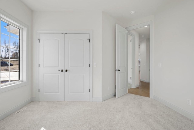 unfurnished bedroom featuring multiple windows, a closet, and light carpet