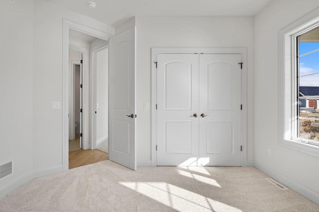 unfurnished bedroom featuring multiple windows, a closet, and light carpet