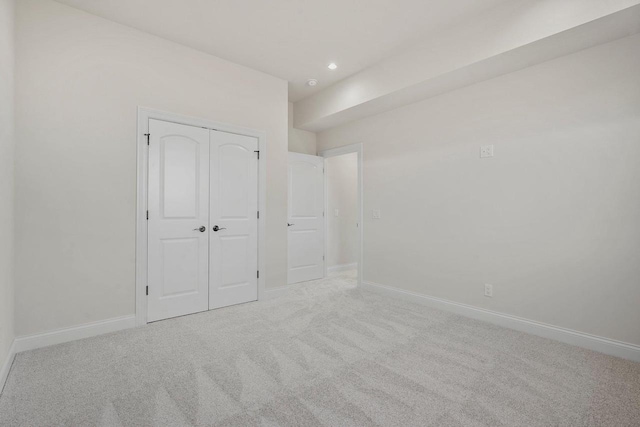 unfurnished bedroom with a closet and light carpet