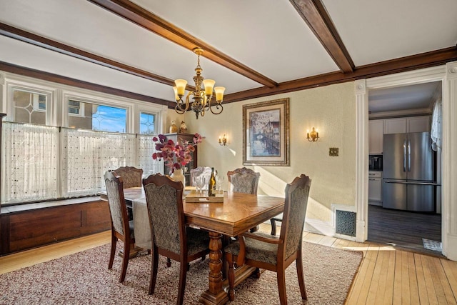 dining space featuring beamed ceiling, crown molding, a chandelier, and light wood-type flooring