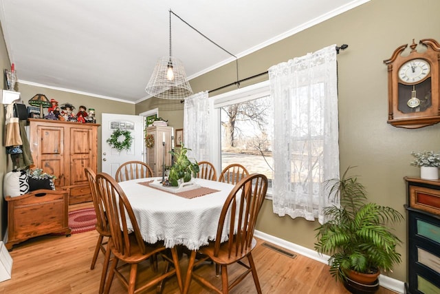 dining area with light hardwood / wood-style flooring and ornamental molding