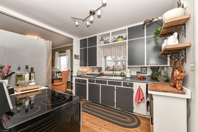 kitchen with sink, electric range oven, light hardwood / wood-style flooring, fridge, and ornamental molding