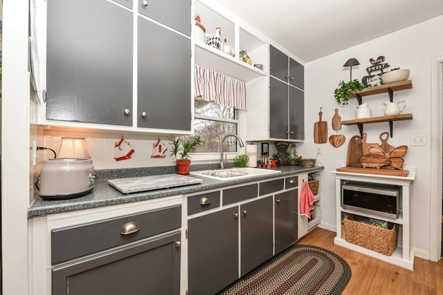 kitchen with sink, decorative backsplash, and light hardwood / wood-style flooring