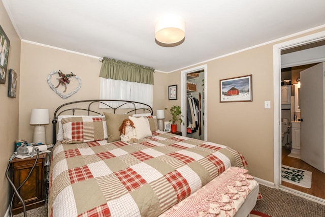 carpeted bedroom featuring crown molding, a walk in closet, and a closet