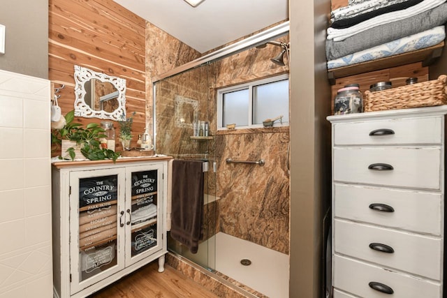 bathroom featuring wood-type flooring, tile walls, and an enclosed shower