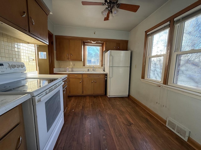 kitchen with sink, white appliances, dark hardwood / wood-style floors, ceiling fan, and backsplash