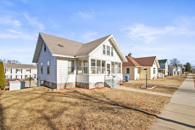 view of front of home with a sunroom and a front yard