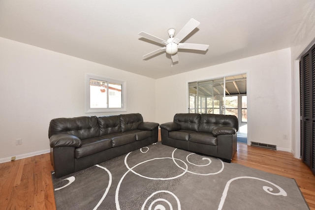 living room with a wealth of natural light, wood-type flooring, and ceiling fan