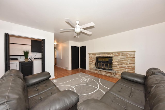 living room with ceiling fan, washer / dryer, a fireplace, and light hardwood / wood-style floors