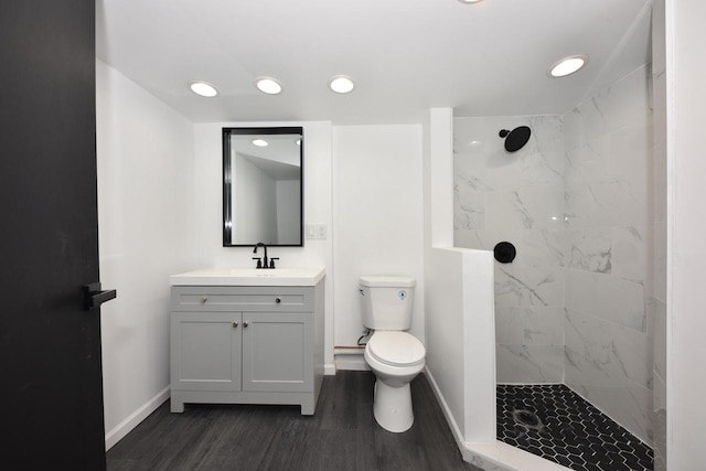 bathroom featuring hardwood / wood-style flooring, vanity, tiled shower, and toilet