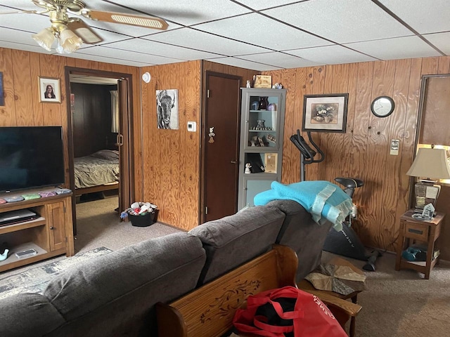 living room with ceiling fan, wooden walls, and carpet flooring