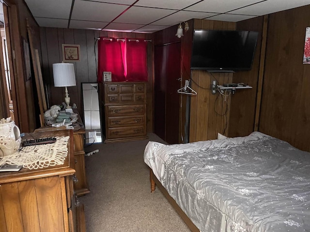 carpeted bedroom featuring wooden walls and a paneled ceiling