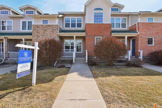 townhome / multi-family property featuring brick siding, a porch, and a front yard