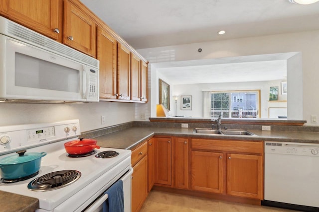 kitchen with white appliances, brown cabinetry, recessed lighting, a sink, and dark countertops