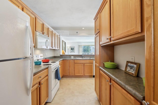 kitchen with white appliances, dark countertops, and a sink