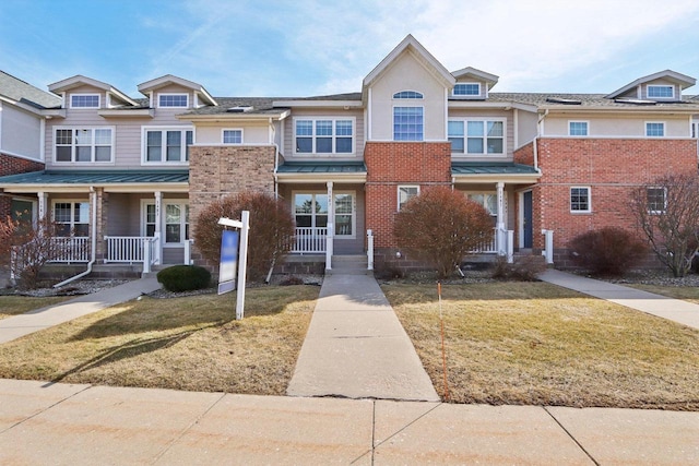 townhome / multi-family property with a standing seam roof, a front lawn, and covered porch